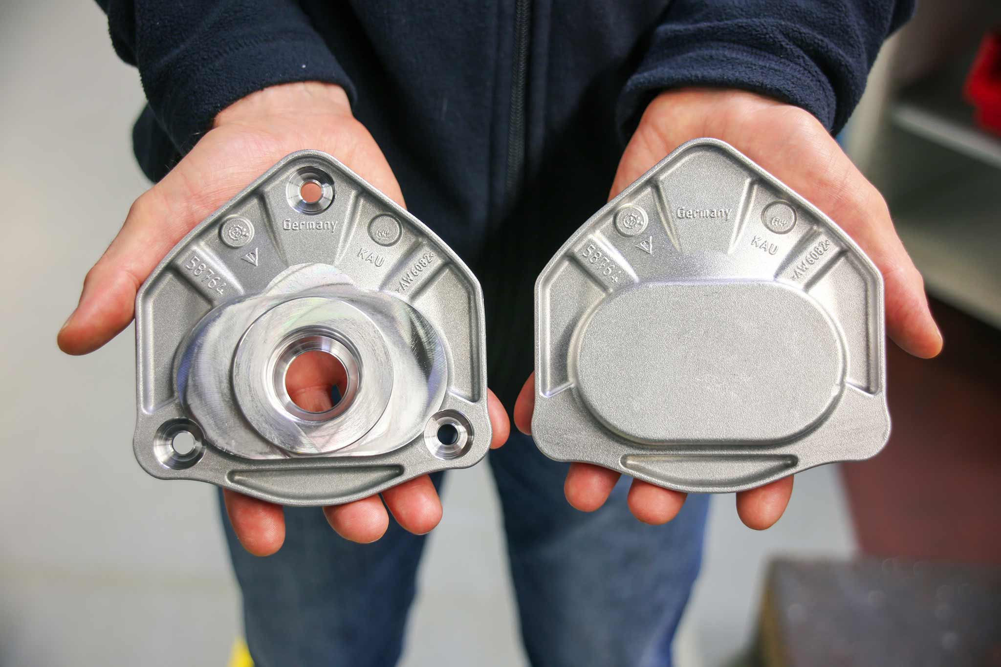 A person shows two strut mounts to the camera.