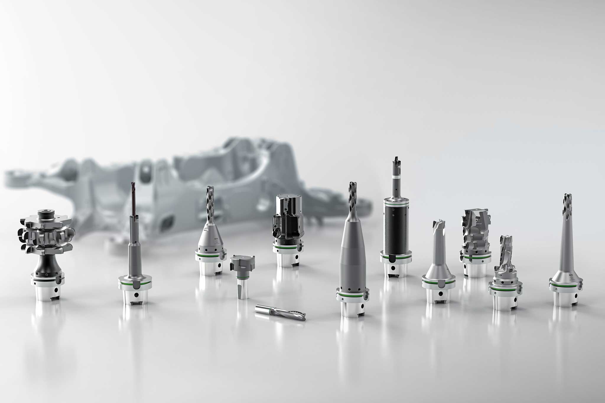 Twelve tools for complete machining are placed in front of a structural part, which is shown as blurred in the background.