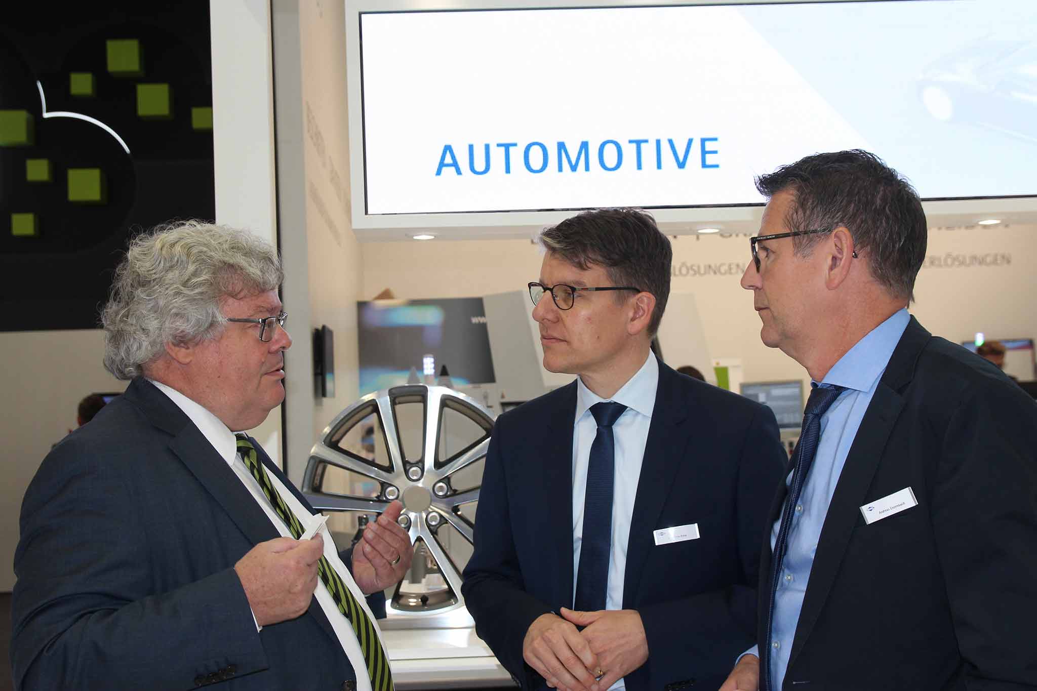 Reinhard Bütikofer having a conversation with Dr Jochen Kress and Andreas Enzenbach in front of the exhibition stand automotive presenter.